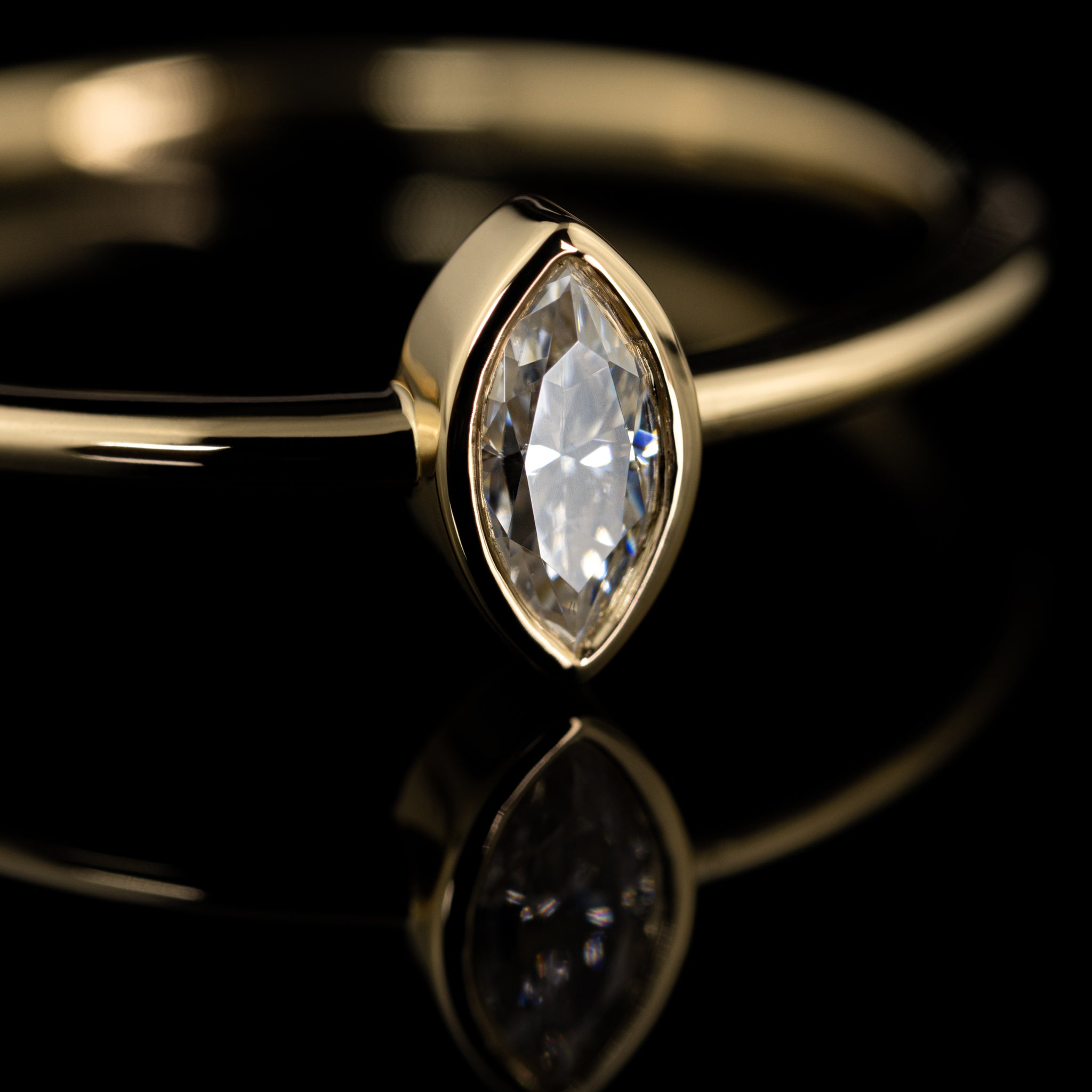 zarter Verlobungsring mit navetteförmigem Diamant in Zargenfassung, Gelbgold poliert, handgearbeitet vom Goldschmied, Nahaufnahme facettierter Mittelstein